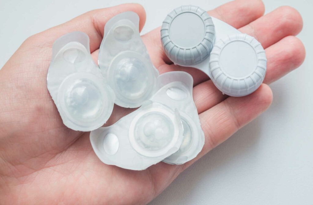 A hand holding a blister pack of contact lenses and a contact lens case