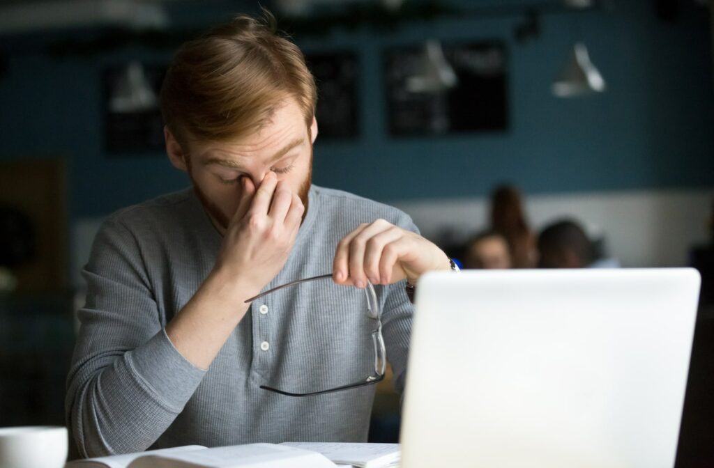 man rubbing his eyes due to digital eye strain from his computer
