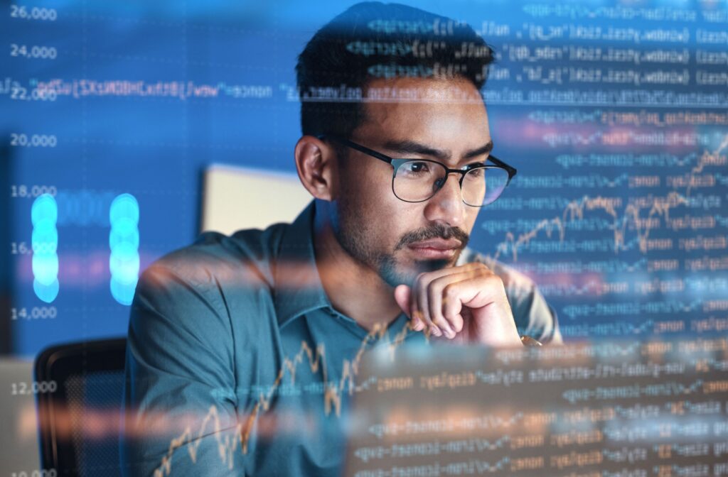 A man wearing glasses looking at his computer screen that is set to dark mode.