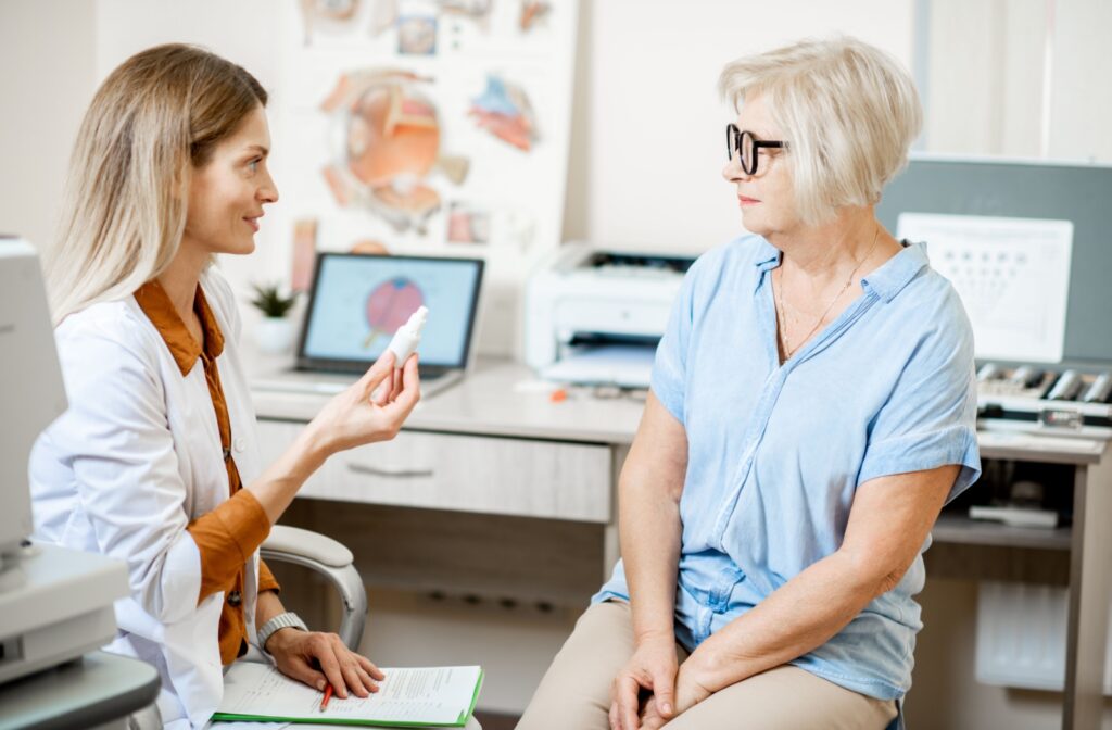 An optometrist holding a bottle of eyedrops while explaining to a patient what to expect after LASIK.