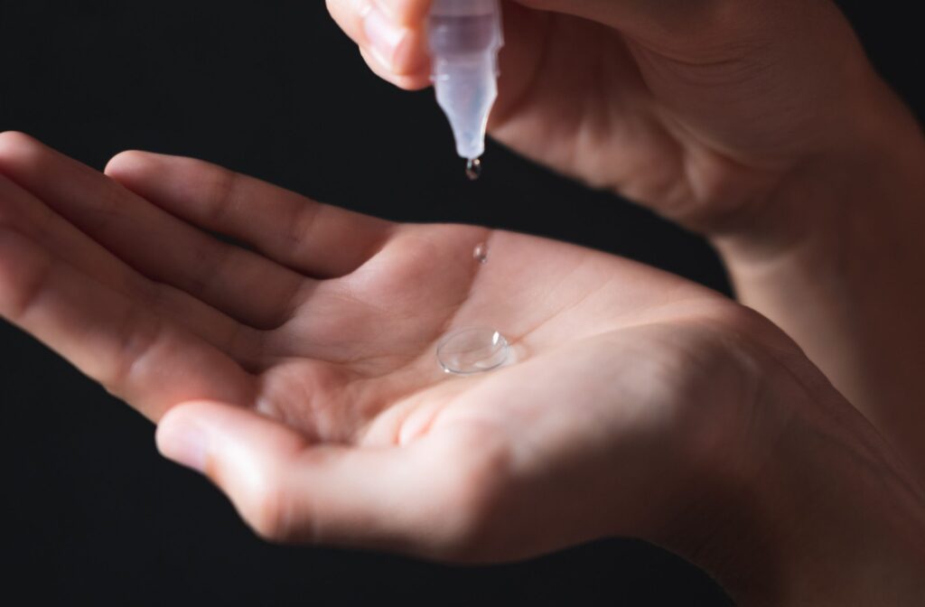 Close-up of a contact lens wearer holding a contact lens in their palm and dropping cleaning solution inside