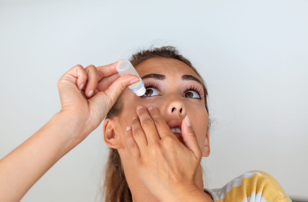 A teen with myopia tilts their head back and squeezes low-dose atropine eye drops into their eyes for myopia management.