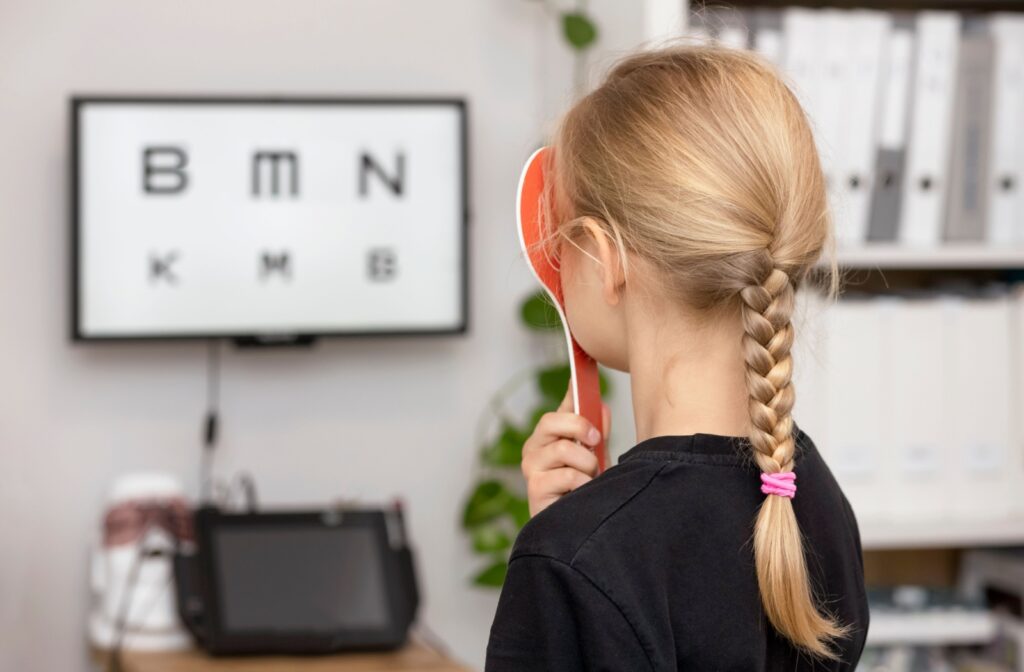 A child looking at an eye chart during an eye exam, monitoring for signs of myopia progression.