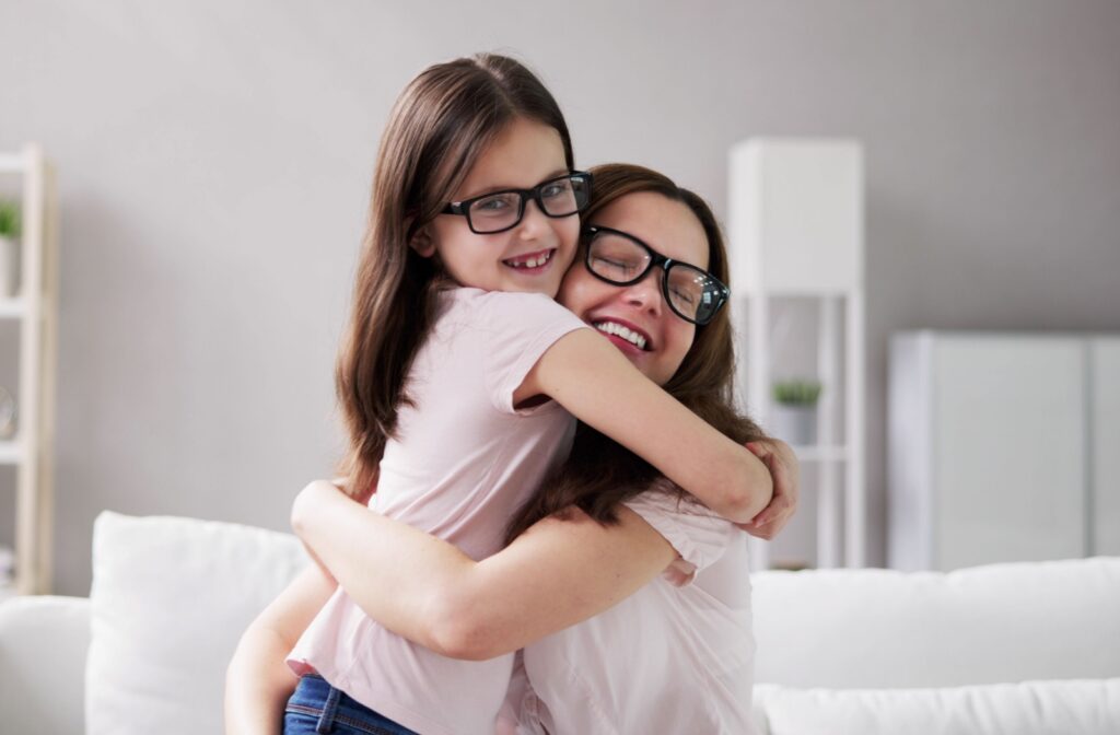A mom and daughter hugging, both wearing glasses.